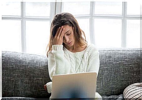 Stressed woman with hand on forehead.