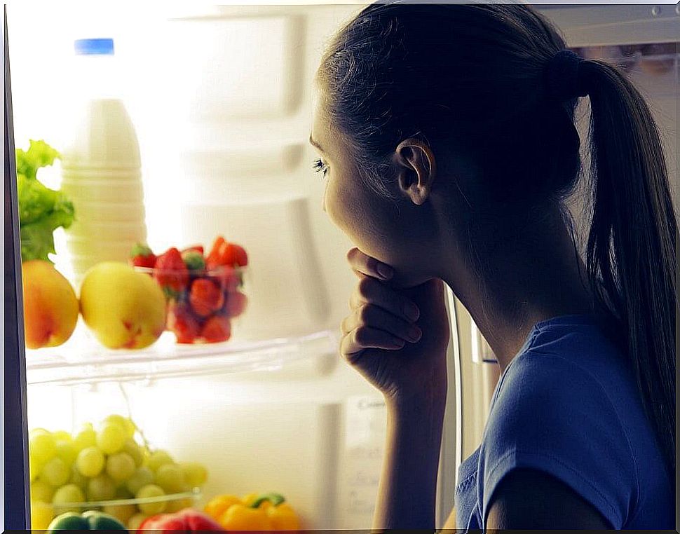 Girl in front of the refrigerator chooses what to eat