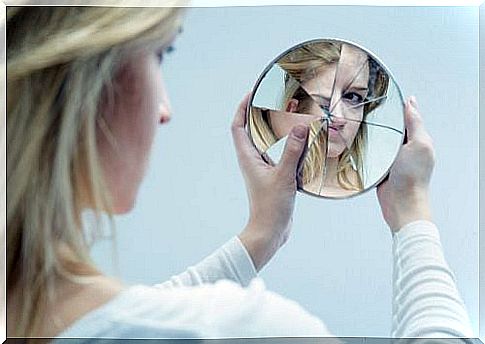 Woman looking at herself in a broken mirror