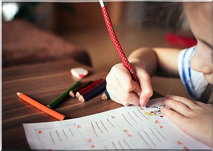 Little girl writes with pencil