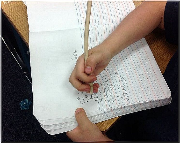 Child writes on lined notebook 